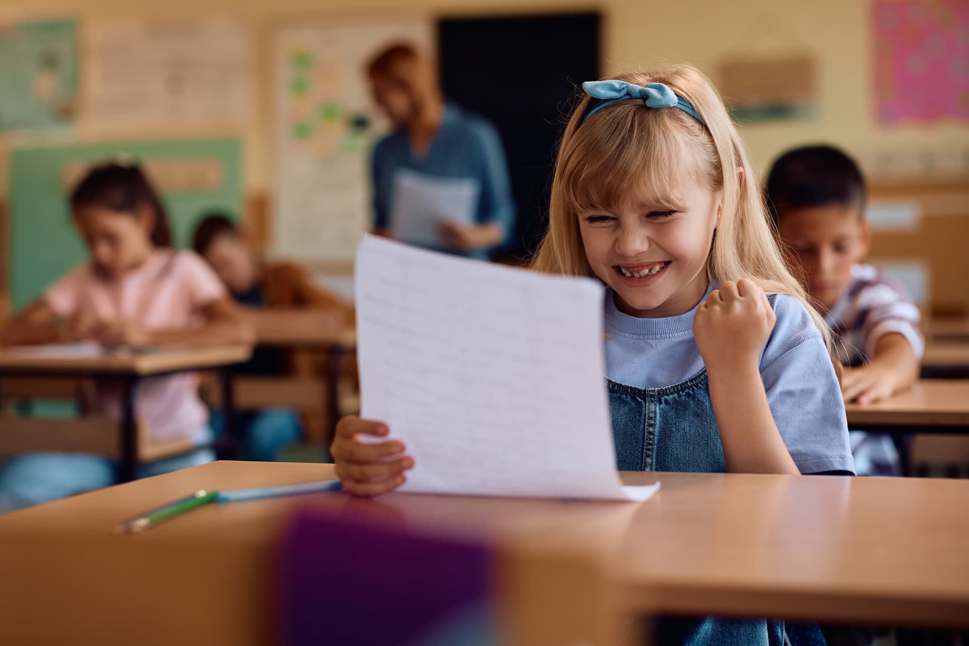 Proud young student smiling while holding achievement certificate in classroom